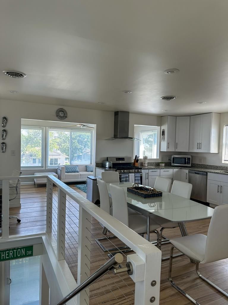 Una cocina moderna con armarios blancos, una mesa de comedor con sillas y vistas al exterior a través de grandes ventanales.