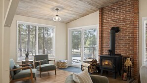Un salón acogedor con chimenea, suelo de madera y ventanas amplias.