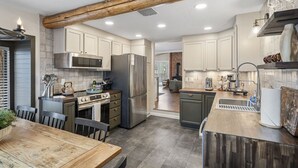 Una cocina moderna con una isla central, electrodomésticos de acero inoxidable y una viga de techo rústica.