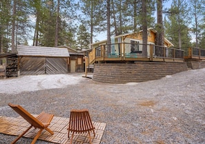 A cabin with a deck, surrounded by trees. - Private Sauna + Hot Tub - Mins to Mt. Bachelor (Bend)