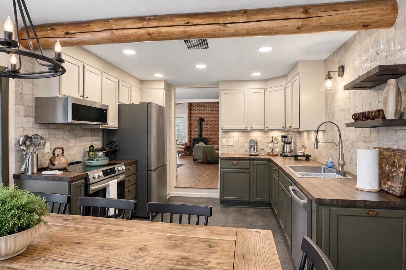 A modern kitchen with a central island, stainless steel appliances, and a brick fireplace in the background.