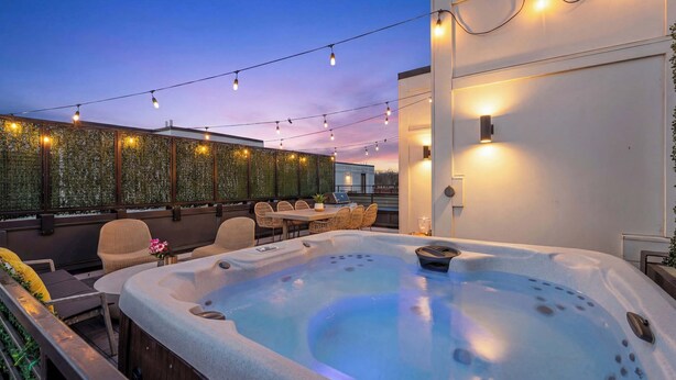 Eine Dachterrasse mit Whirlpool, Lichterketten und Sitzgelegenheiten im Freien.