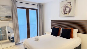 A hotel room with a large bed, a wooden headboard, and a painting on the wall. - 1 Bed - Sleeps 2 - City Centre - Free Parking (St Albans)