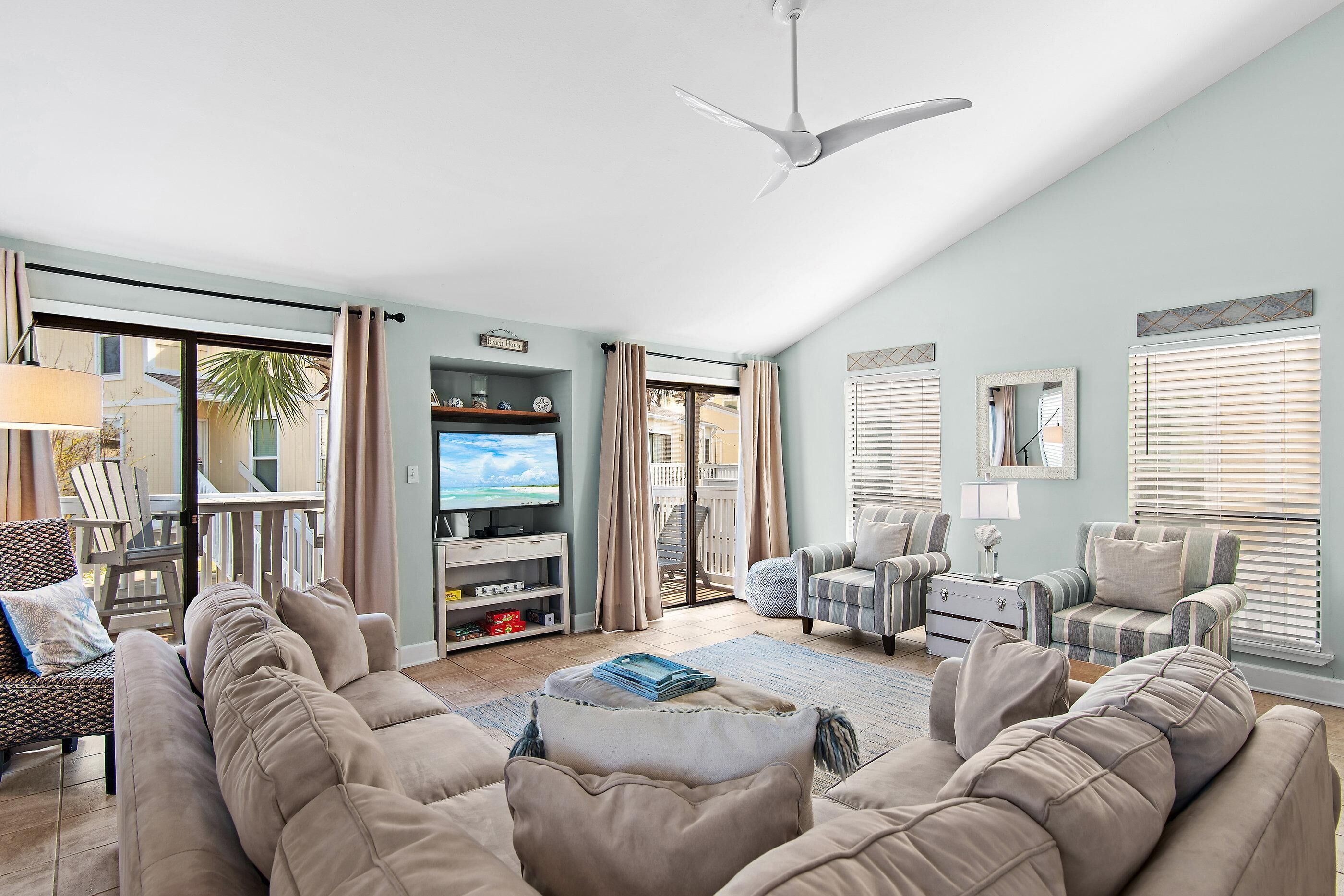 Una sala de estar con sofá, sillones, televisor y ventilador de techo.