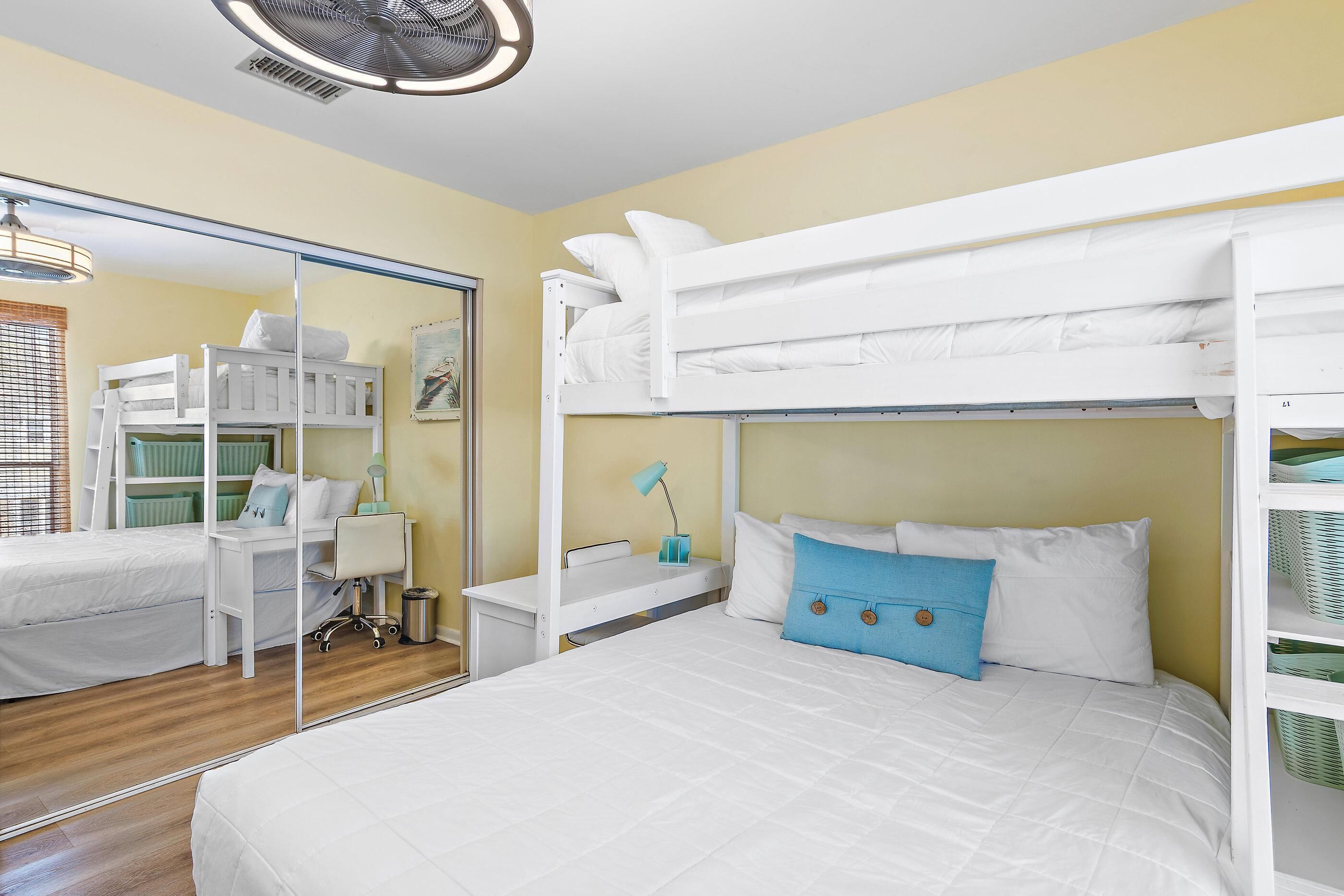 A room with bunk beds, a desk, a chair, a lamp, and a mirror.