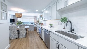 Une cuisine moderne avec des meubles blancs, un robinet noir et un plancher en bois.