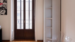 Una stanza con pavimento in legno, una porta con finestra e un'unità di scaffalatura bianca.