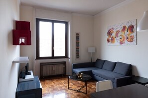A modern living room with a blue sofa, a coffee table, a lamp, and a radiator. - Bright three-room apartment High floor near the Arch of Peace (Milano)