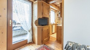 A compact kitchen with wooden cabinets, a built-in television, and a small countertop. - Casa Col 3, a charming two-room apartment (Cortina d´Ampezzo)