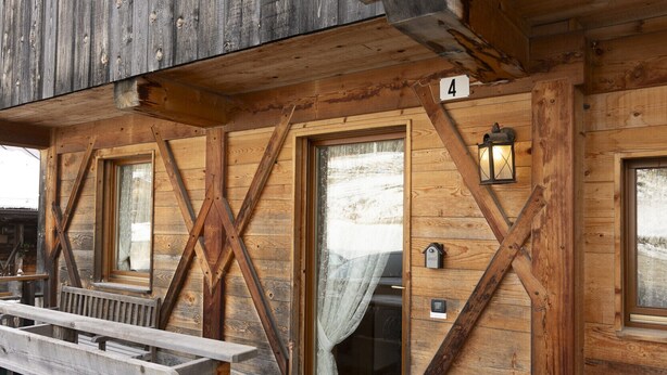 A wooden building with a stone foundation, wooden benches, and a number '4' sign. - Casa Col 3, a charming two-room apartment (Cortina d´Ampezzo)