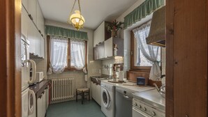 Pieni, käytännöllinen keittiö, jossa on pesukone, liesi ja pesuallas.