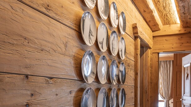 A wooden wall with a row of silver plates and a wooden sled. - Casa Merisanda, comfortable and surrounded by Natur (Cortina d´Ampezzo)