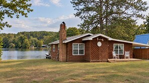 A cabin with a chimney, a large window, and a door with a decorative plate. - Lakeside! on Lake sleeps 5, close to I 75 interstate, Rest, Relax, Fish, Repeat (Tunnel Hill)