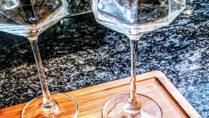 Deux verres à vin sur un plateau en bois portant une inscription gravée.
