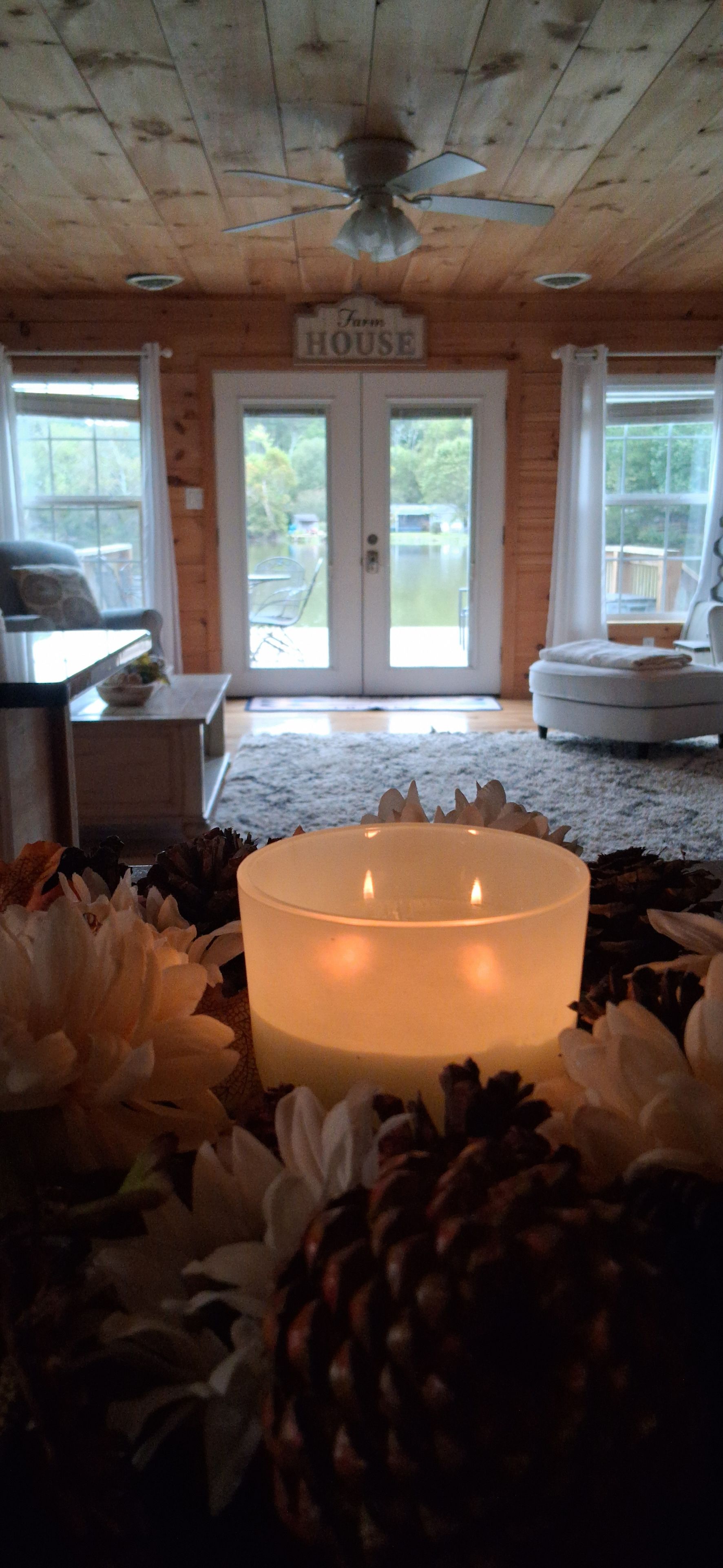 Une pièce avec un plafond en bois, une enseigne indiquant « FERME », une porte et une table sur laquelle se trouvent une bougie et des fleurs.