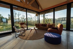Ein modernes Wohnzimmer mit großen Fenstern, einem Sofa, einem Sessel und einem Couchtisch.