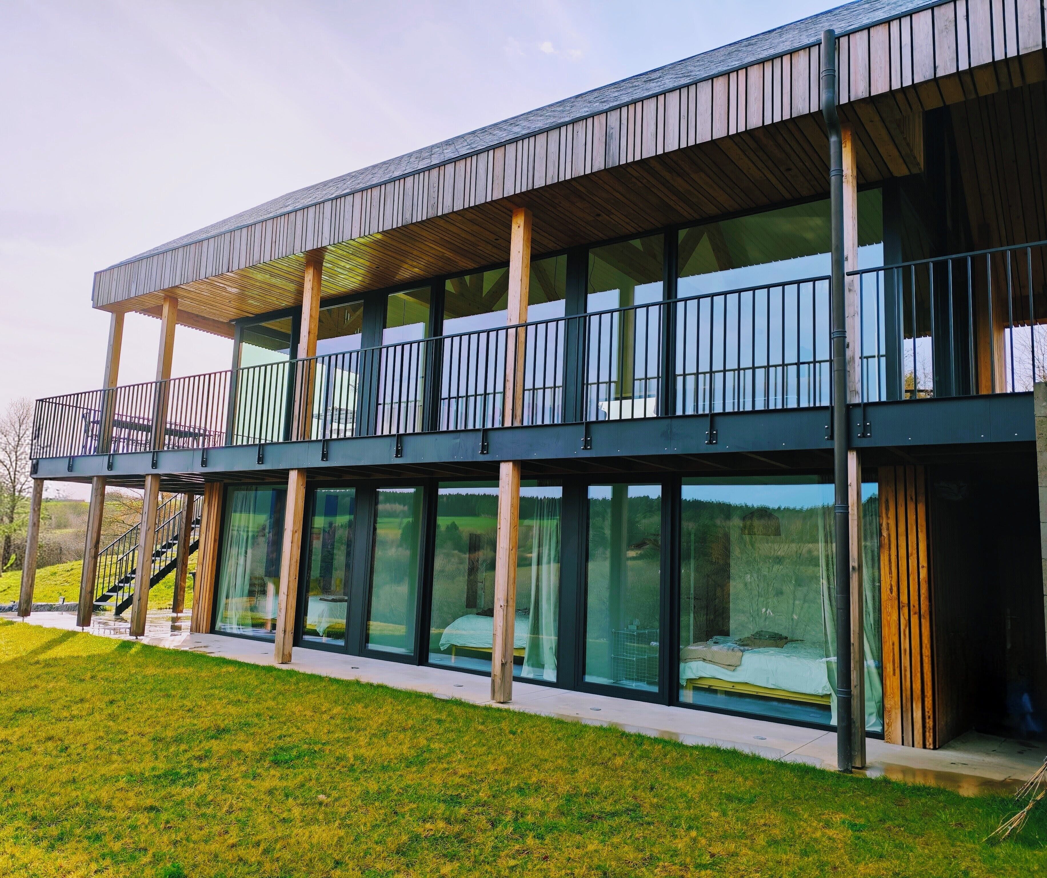 A modern building with a balcony, large windows, and a wooden deck.