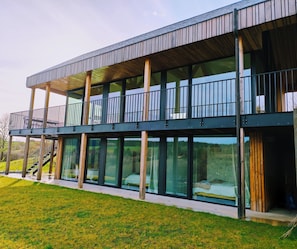 Ein modernes Gebäude mit Balkon, großen Fenstern und einer Holzterrasse.