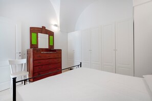Una camera da letto con un letto, una cassettiera, una sedia e un armadio.