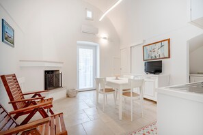 Una cucina moderna con mobili bianchi, un'area pranzo con sedie bianche e un camino.