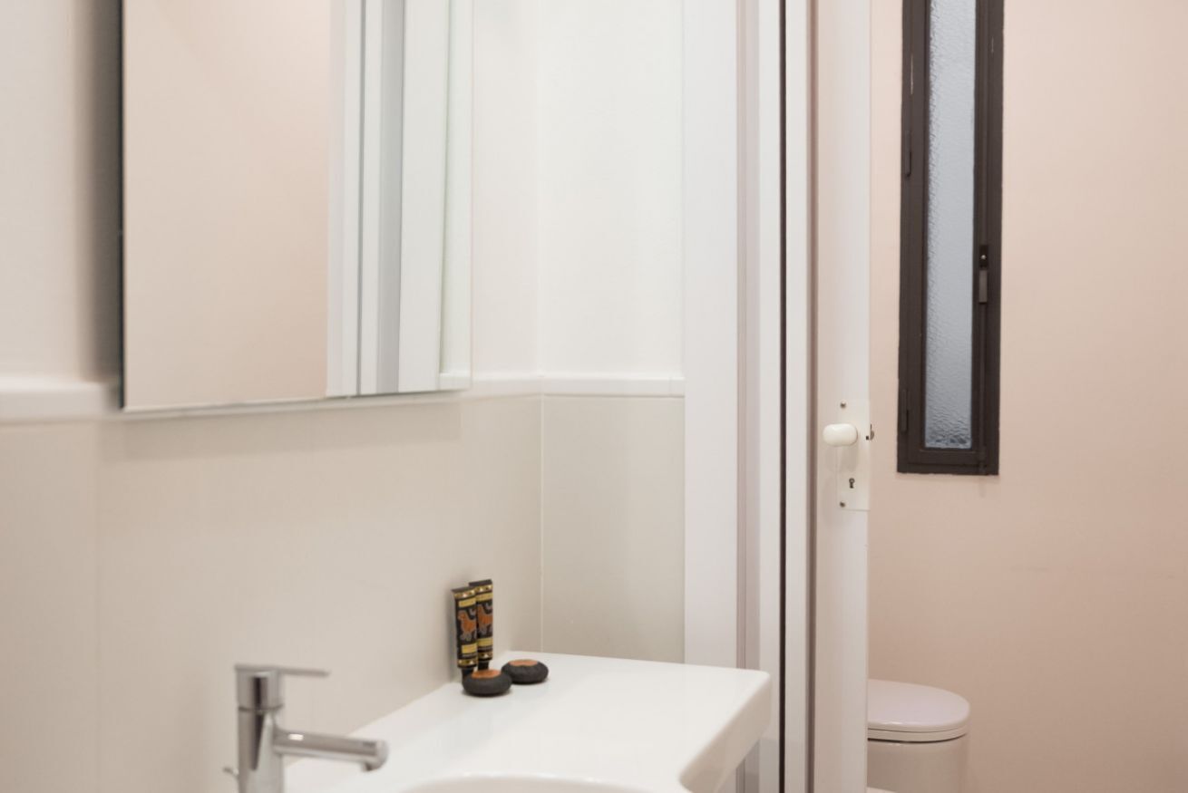 Un baño con un lavabo blanco, un espejo y un inodoro.