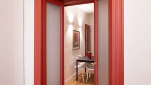 A narrow hallway with red-framed doors leading to a dining area with a black table and white chairs. - Characteristic two-room apartment Colonne di San Lorenzo - Mirable PM (Milano)