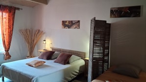 A bedroom with a bed, bedside tables, a lamp, a wall art piece, and a window with curtains.