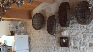 A kitchen with a stone wall, a wooden ceiling, and a counter with fruit bowls.