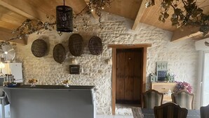 A rustic kitchen with a stone wall, a wooden door, and a dining area with chairs and a table.