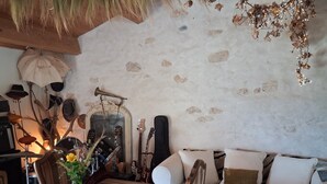 A room with a rustic stone wall, a wooden dining table, a zebra-patterned sofa, and a brass trumpet mounted on the wall.
