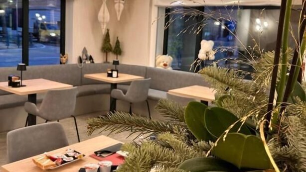 A modern restaurant interior with wooden tables, grey chairs, and decorative plants. - HOTEL CENTRALE RESANA (Resana)