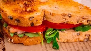A sandwich with visible layers of bread, lettuce, tomato, and a creamy filling, served on a paper plate. - HOTEL CENTRALE RESANA (Resana)