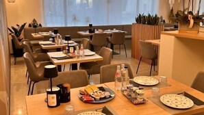 A modern dining area with multiple tables, chairs, and a large window providing natural light. - HOTEL CENTRALE RESANA (Resana)