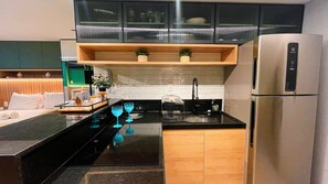 Eine moderne Küche mit schwarzen Arbeitsplatten, einem Edelstahlkühlschrank und einer Holztischinsel.