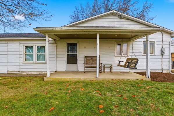 A single-story house with a covered porch, a swing set, and a small bench. - Trackside Vacation Home - 9 min. to Sight & Sound! (Ronks)