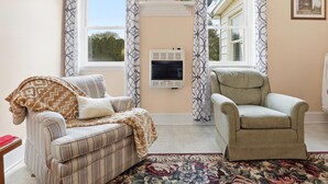 A cozy living room with a striped sofa, a beige armchair, and a patterned rug. - Trackside Vacation Home - 9 min. to Sight & Sound! (Ronks)