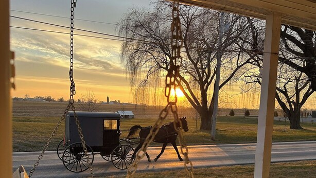 A horse-drawn carriage on a road with a sunset in the background. - Trackside Vacation Home - 9 min. to Sight & Sound! (Ronks)