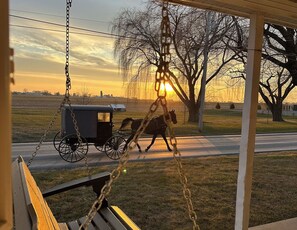 A horse-drawn carriage on a road with a sunset in the background. - Trackside Vacation Home - 9 min. to Sight & Sound! (Ronks)