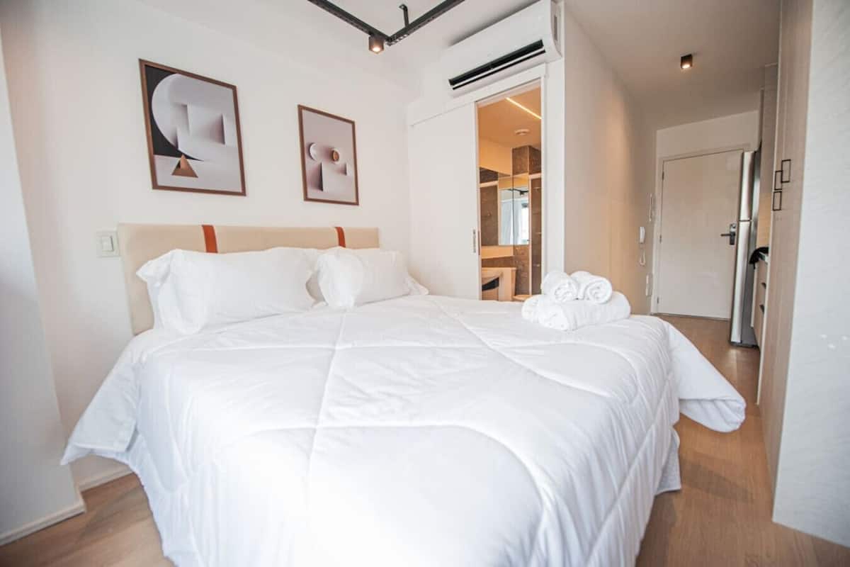 Een moderne hotelkamer met een groot bed, een kledingkast en een badkamer die door een open deur zichtbaar is.