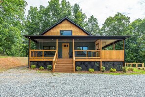 A two-story wooden cabin with a front porch, a staircase, and a fenced deck. - Dreamcatcher Cabin~Hot Tub, Mtn Views & Fire Pit! (Burnsville)