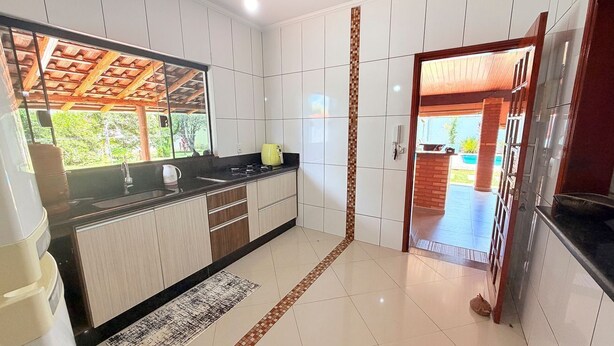 Cozinha com armários brancos, bancada preta e teto de madeira.