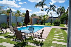 Un giardino con piscina, mobili da patio e palme.