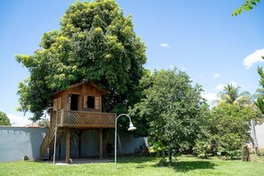 Una casa in legno con un balcone, immersa nel verde e sotto un cielo azzurro.