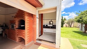 Cozinha externa com forno de tijolos, pia e bancada.