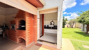 Cucina esterna con forno a mattoni, lavello e piano di lavoro.