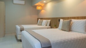 A hotel room with two beds, a wooden headboard, a wall-mounted air conditioner, and a small plant.