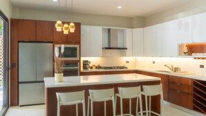 A modern kitchen with a central island, bar stools, and pendant lighting.