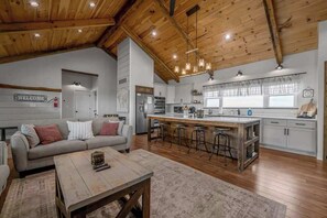 Amplia sala de estar con sofá, mesa de centro e isla de cocina con taburetes.