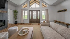 Una sala de estar moderna con chimenea, un sofá, una mesa de centro y un ventanal con vistas.