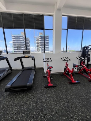 Une salle de sport équipée de tapis de course, de vélos d’appartement et d’autres appareils d’exercice.